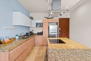A modern kitchen with granite countertops, a built-in oven, and a stainless steel refrigerator.