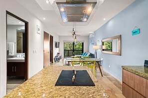 A modern kitchen with a granite countertop, a built-in stove, and a dining area with yellow chairs. - Spectacular Penthouse: Private  Rooftop and Pool (Tulum)