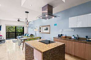 Een moderne keuken met granieten aanrechtbladen, een inbouwfornuis en houten keukenkastjes.