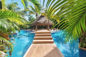 A swimming pool with a wooden deck leading to a thatched-roof structure, surrounded by palm trees. - Spectacular Penthouse: Private  Rooftop and Pool (Tulum)