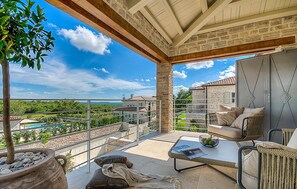 A spacious balcony with a view of a pool and surrounding buildings, furnished with a sofa and a table. - Gorgeous home in Kanfanar (Kanfanar)