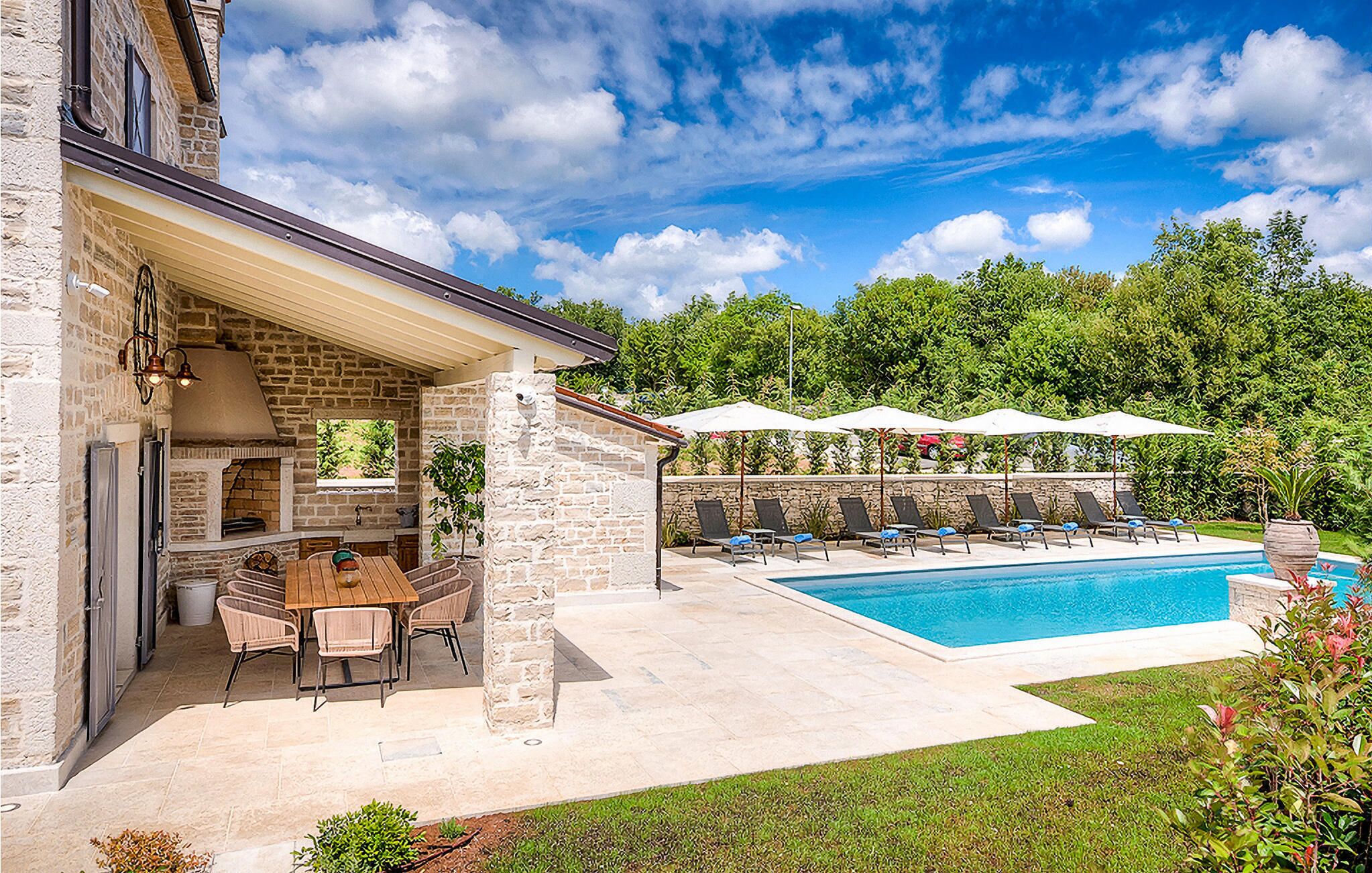 A backyard with a pool, outdoor seating, and a stone patio.