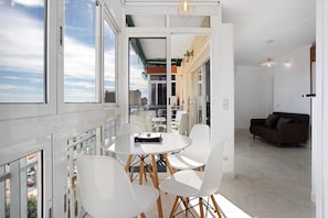 Un interior moderno con balcón, una zona de comedor con mesa y sillas, y un espacio de estar con sofá.