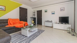 En moderne stue med sofa, sofabord, fjernsyn og pynt.