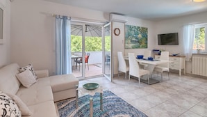 A modern living room with a sofa, a coffee table, and a dining area with chairs and a table. There is a sliding glass door leading to an outdoor patio. - Stunning home in Kukci - Nova Vas (Kukci - Nova Vas)