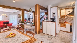 A modern kitchen with a wooden island, a dining area with a table set for two, and a living room with a red sofa. - Stunning home in Kukci - Nova Vas (Kukci - Nova Vas)