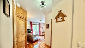 Une porte en bois, un lit, une table, une lampe, un luminaire au plafond et un élément décoratif fixé au mur.
