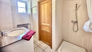 Une salle de bain équipée d’un lavabo, d’un miroir, d’un porte-serviettes, d’une douche et d’une porte en bois.