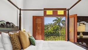 Un dormitorio con una cama grande, cabecera de madera y un balcón con vista a palmeras.