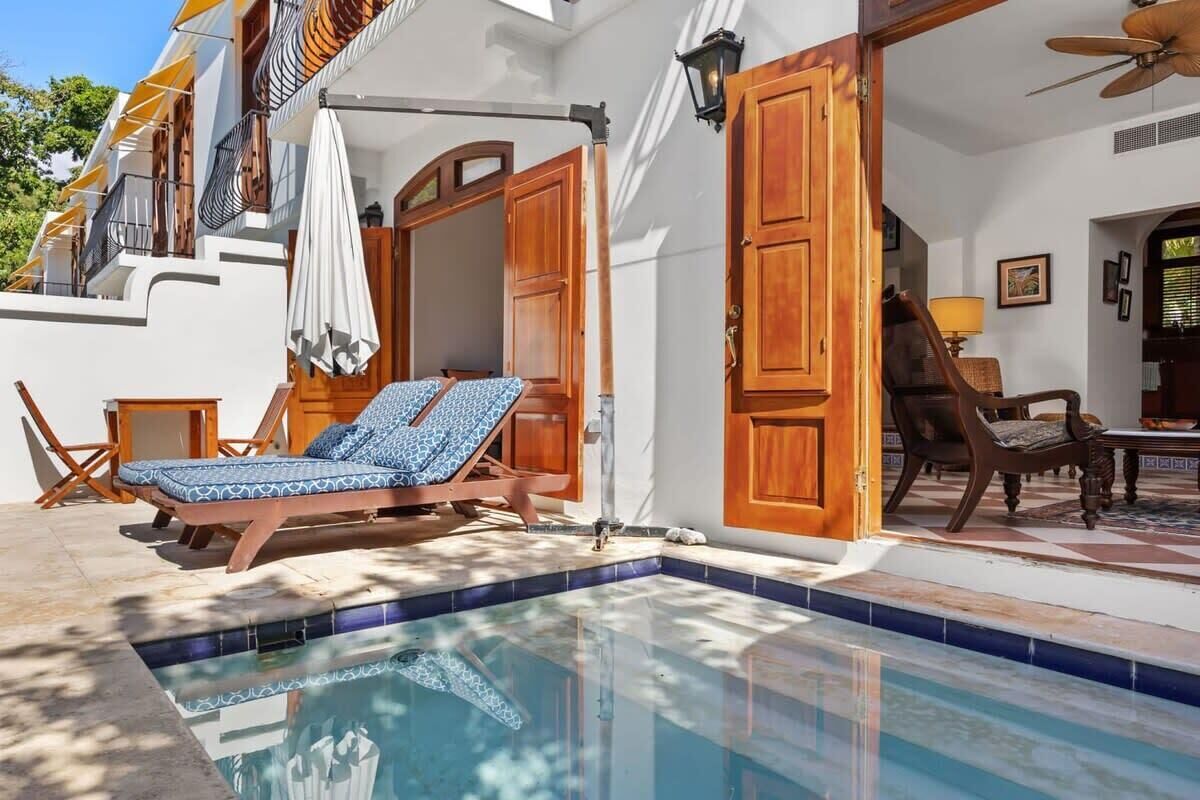 A poolside area with a lounge chair, a small table, and a wooden door.