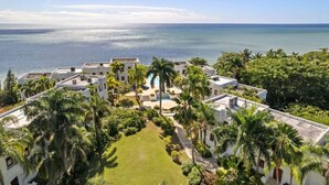 Un resort con varias edificaciones blancas, una piscina y vista al océano.