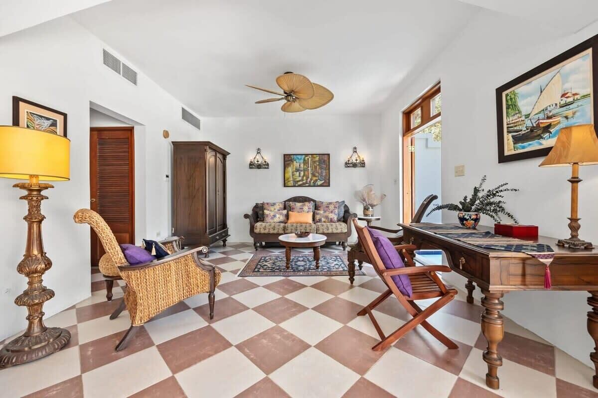 A spacious living room with a checkered floor, a sofa, a coffee table, and a desk with a lamp.