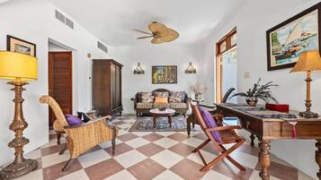 A spacious living room with a checkered floor, a sofa, a coffee table, and a desk with a lamp.