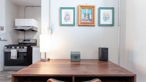 A dining area with a wooden table, a lamp, a small blue box, and framed pictures on the wall. - ArtMusicEntertainment+Downtown+PetsOK+Walk2Shore (Corpus Christi)