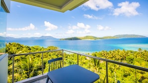 Un balcón con vistas a un paisaje tropical, que incluye una masa de agua y vegetación.