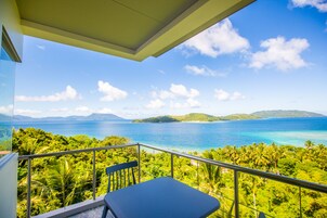 Un balcón con vistas a un paisaje tropical, que incluye una masa de agua y vegetación.