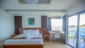 Una habitación de hotel con una cama grande, un escritorio y vista al mar.