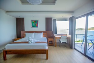 Una habitación de hotel con una cama grande, un escritorio y vista al mar.