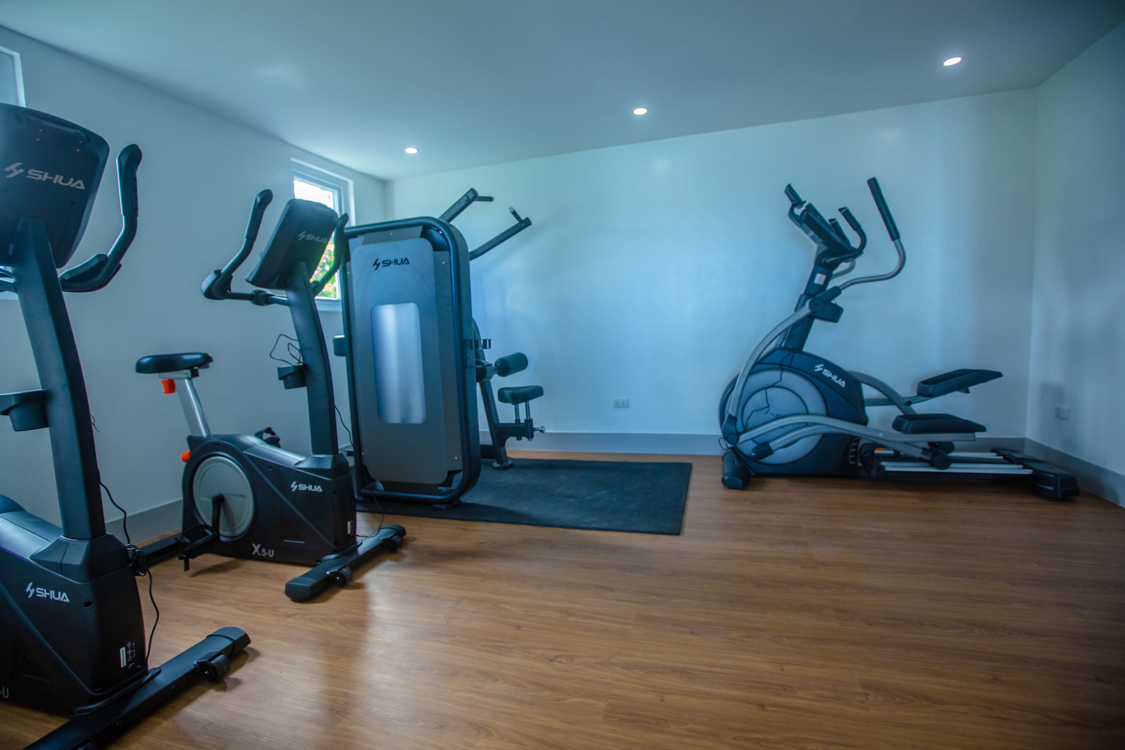 Un gimnasio en casa con equipo de ejercicio, incluyendo una bicicleta estática, una elíptica y una máquina de pesas.