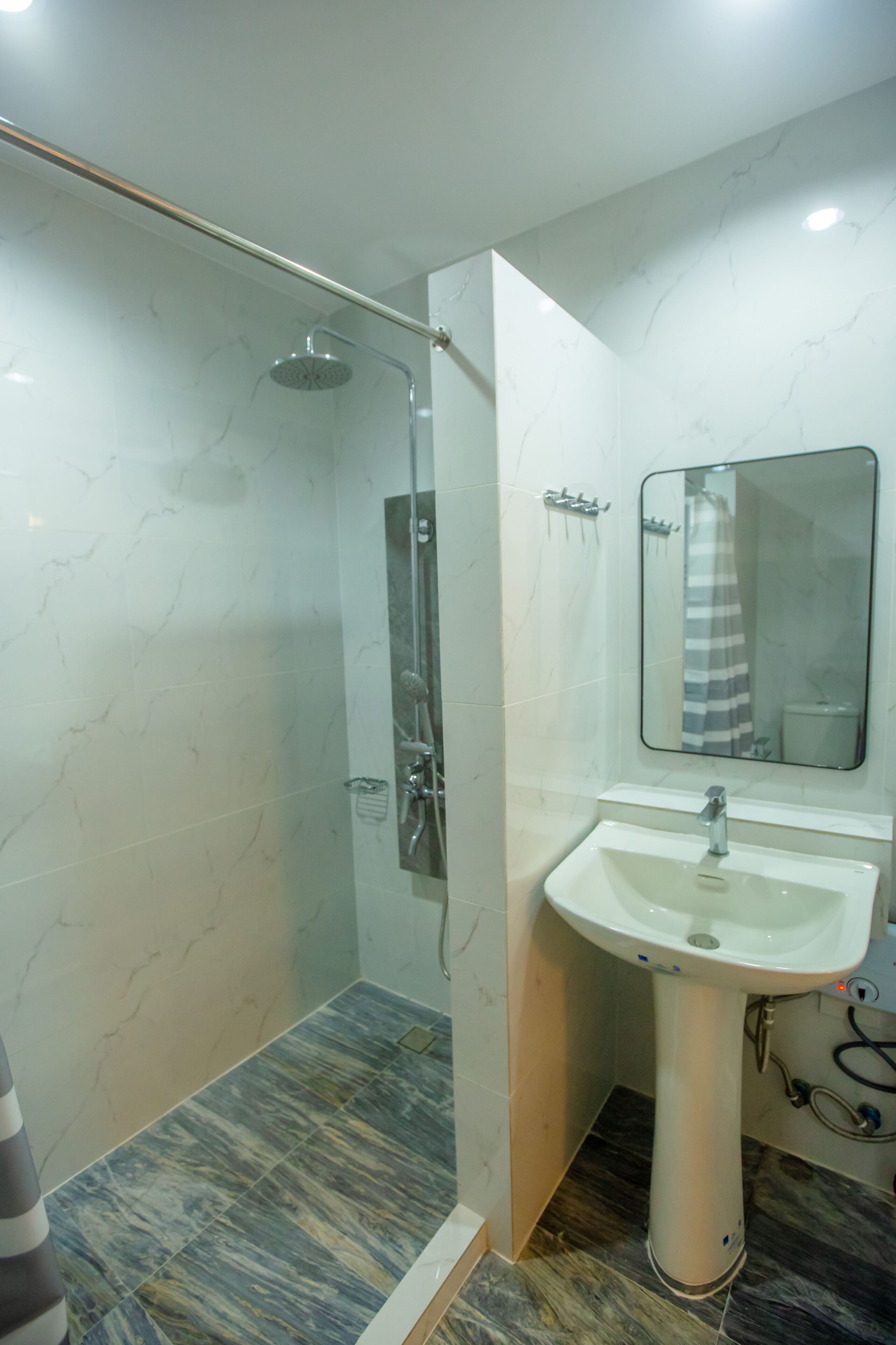 A bathroom with a shower, a sink, and a mirror.