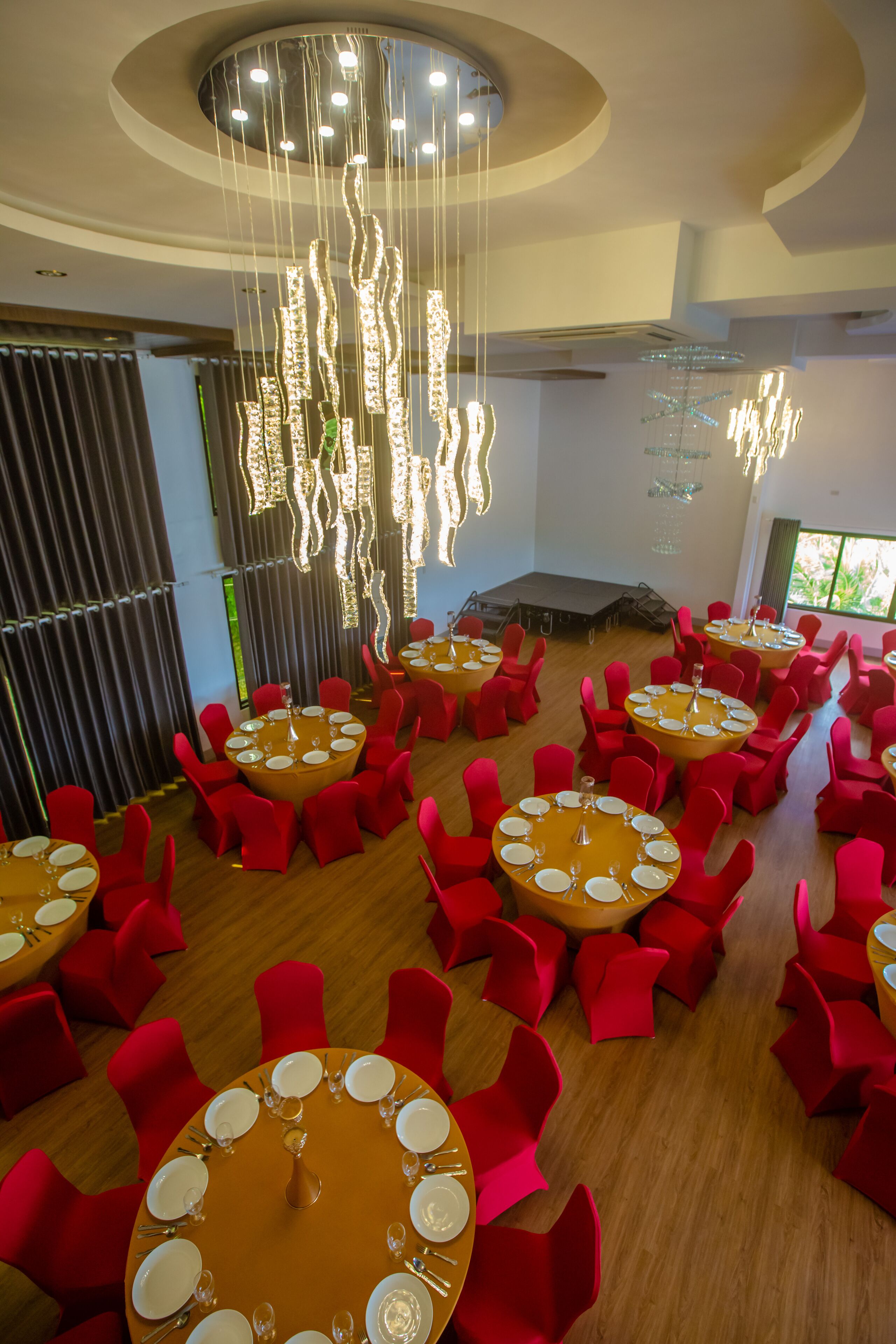 A spacious dining area with multiple round tables set for dining, surrounded by red chairs.