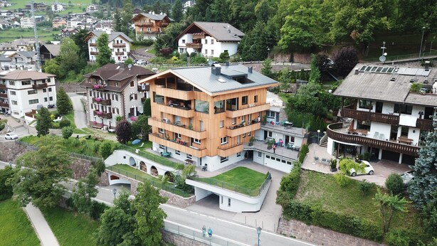 A multi-story building with balconies, a green roof, and a pedestrian bridge. - Apartment 'Villa Hubertus Valtoi' with Mountain View, Balcony and Wi-Fi (Ortisei (BZ))