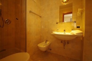 A bathroom with a shower, bidet, sink, and toilet.