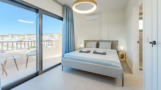 Een moderne slaapkamer met een groot raam, een bed met hoofdbord en een ronde lamp.