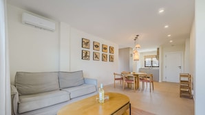 Een woonkamer met een bank, een houten salontafel en een eethoek met stoelen en een tafel.