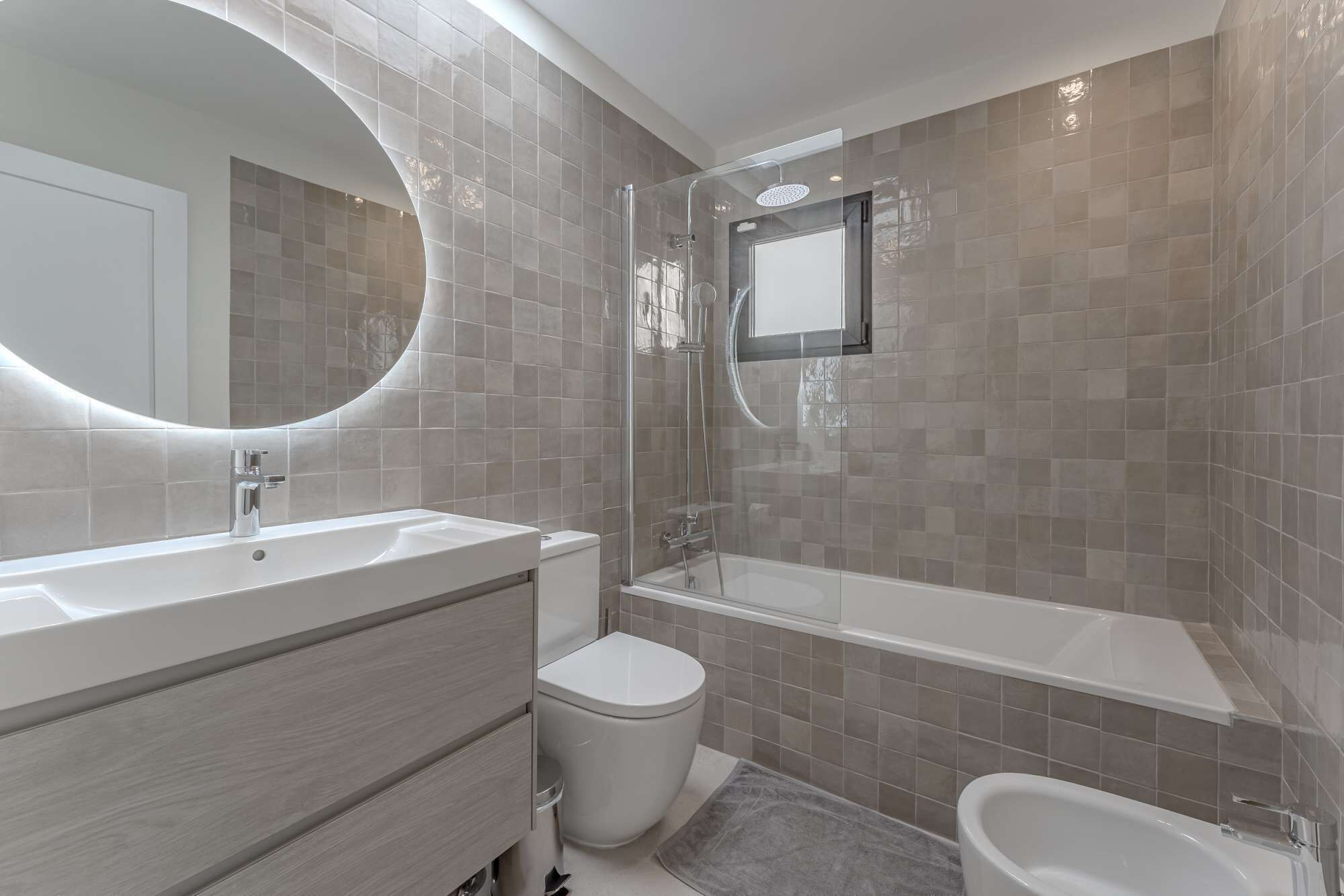 Ein modernes Badezimmer mit Waschtisch, Toilette und Badewanne.