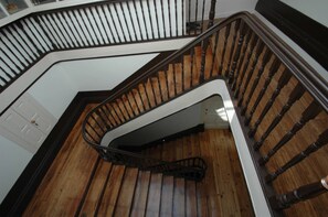 A wooden staircase with a white handrail and black balusters, leading to a landing with a white door.