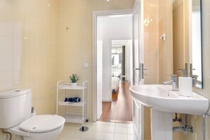A modern bathroom with a toilet, sink, and a small shelf with a plant.