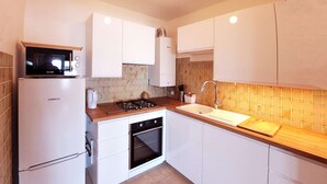 Une cuisine moderne avec des meubles blancs, un four à micro-ondes, une cuisinière, un four et un évier.