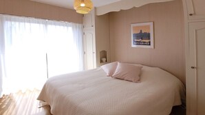 Une chambre avec un grand lit, un luminaire fixé au mur et un tableau encadré.