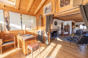 A spacious wooden interior with a fireplace, seating area, and a dining table. - Chalet Le Solli – Panoramic View of the Mont-Blanc Range (Saint gervais les bains)