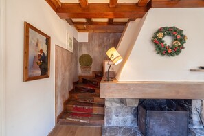 A staircase with wooden steps and a carpet, leading to a stone fireplace with a metal grate.