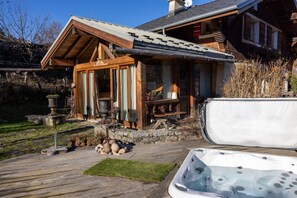 Une cabane en bois dotée d’un bain à remous, d’un escalier en pierre et de mobilier d’extérieur.