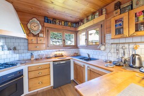 Une cuisine avec des meubles de rangement en bois, une horloge et divers appareils de cuisine.