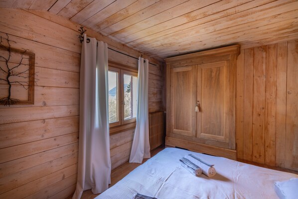 Une pièce en bois avec un lit, un radiateur et une fenêtre avec des rideaux.