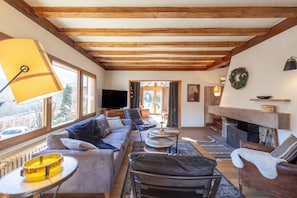 A cozy living room with a sofa, chairs, a fireplace, and a television.