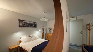 Une chambre à coucher comprenant un lit, une table de chevet, une commode et un miroir.