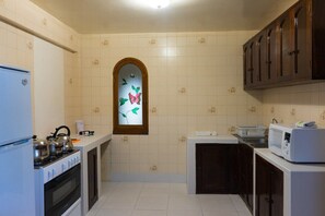 Functional kitchen with gas stove, oven, microwave, and sink, offering ample storage and workspace.