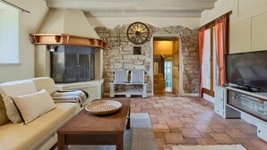 A cozy living room with a stone wall, a wooden bench, a sofa, a coffee table, and a television. - Awesome home in Pazin (Pazin)