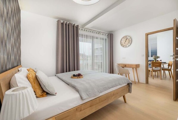 A modern bedroom with a wooden bed, a bedside table, a desk, and a chair.