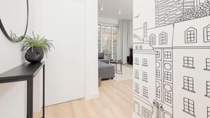 Una sala de estar moderna con un sofá gris, una mesita redonda y una planta en una consola negra.