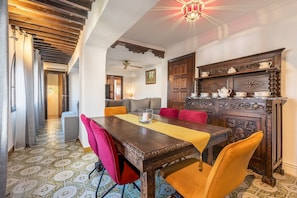 A dining area with a wooden table, red and yellow chairs, a patterned floor, and a decorative cabinet. - Holiday Home "Carmen San Andrés" with Mountain View, Private Terrace & Wi-Fi (Granada)
