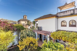 A courtyard with a pergola, a white building with arched windows, and a church in the background. - Holiday Home "Carmen San Andrés" with Mountain View, Private Terrace & Wi-Fi (Granada)