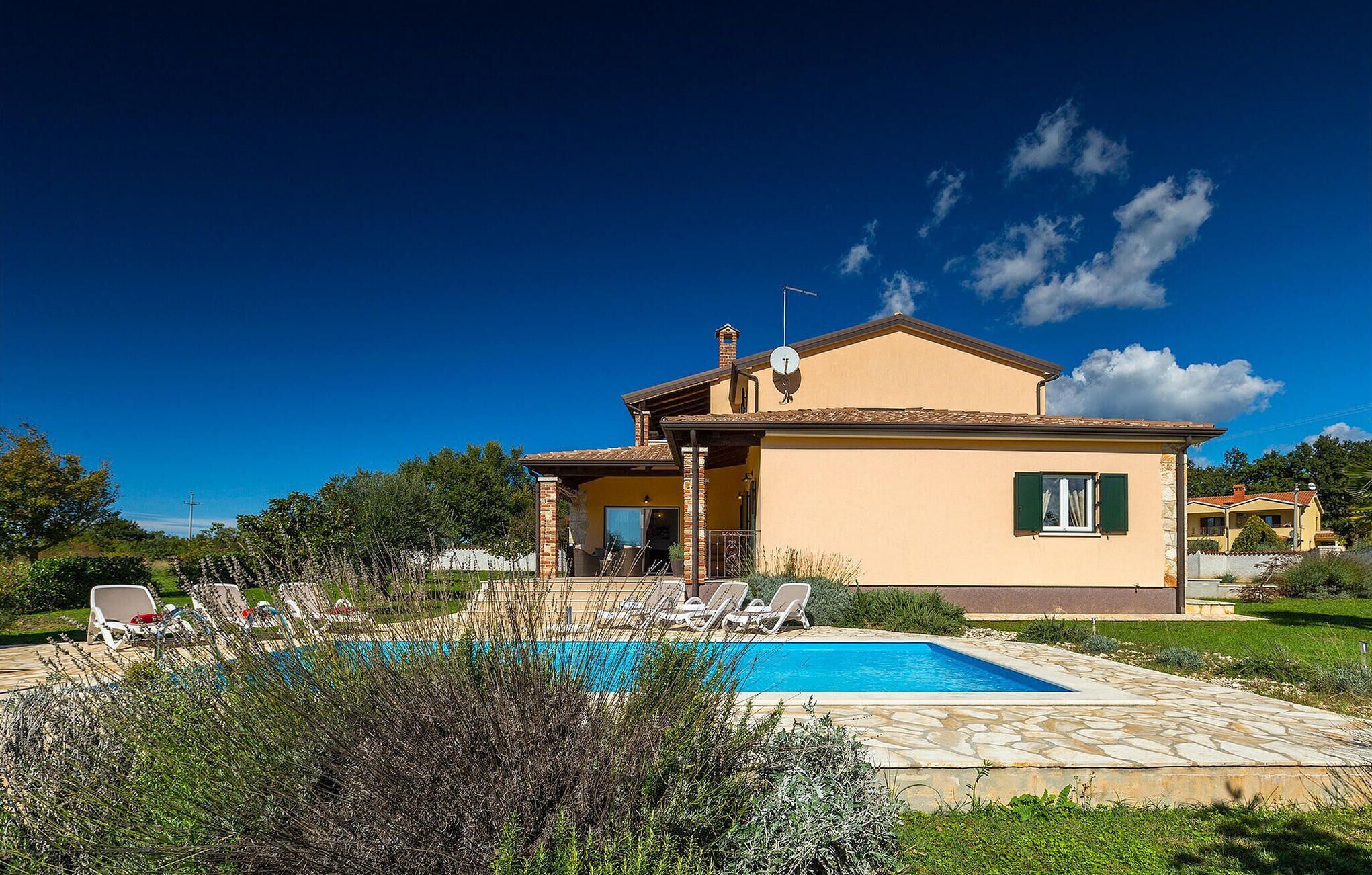 Une maison à deux étages avec une piscine, un patio couvert et un jardin.