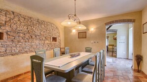 A dining area with a stone wall, a wooden table, and chairs. There is a chandelier above the table and a doorway leading to another room. - Gorgeous home in Svetvincenat with WiFi (Svetvincenat)