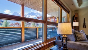 A room with large windows, a wooden ceiling, a sofa, a lamp, and a view of mountains. - Panoramic Views - 3 Bedrooms in White Spruce Lodge (Canmore)
